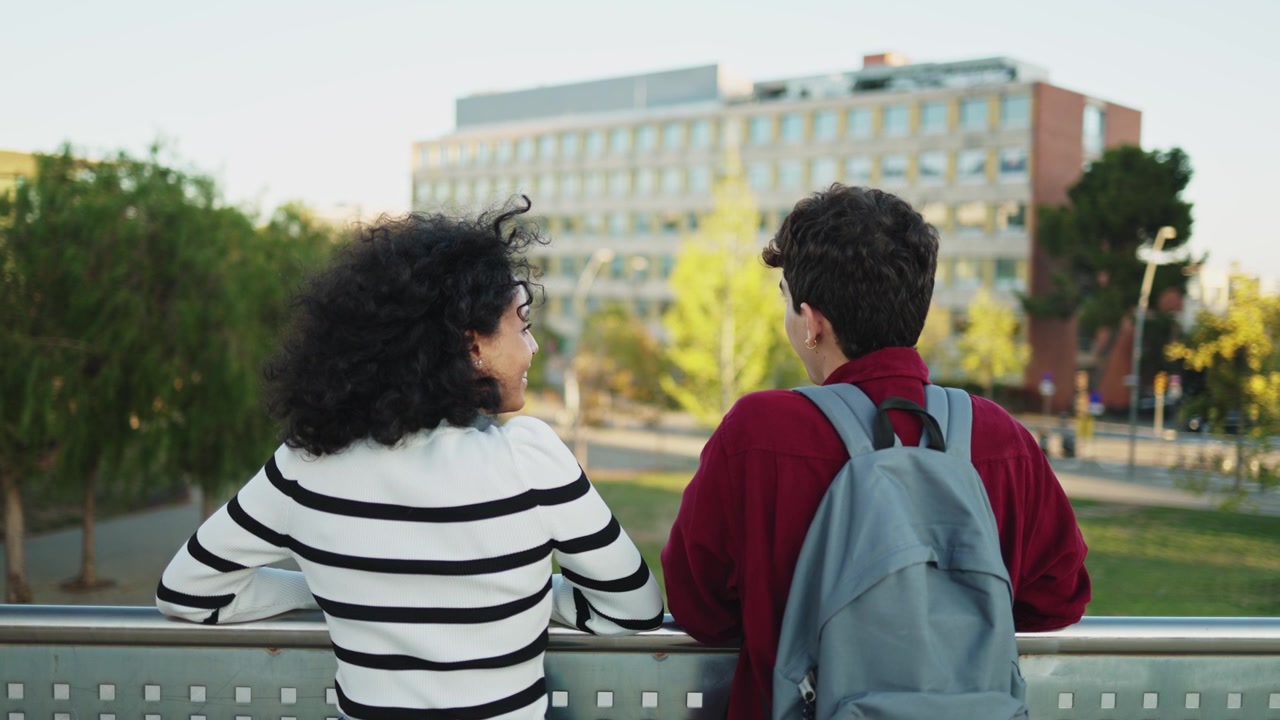 Two Students Talking While Leaning on a Railing Outdoors