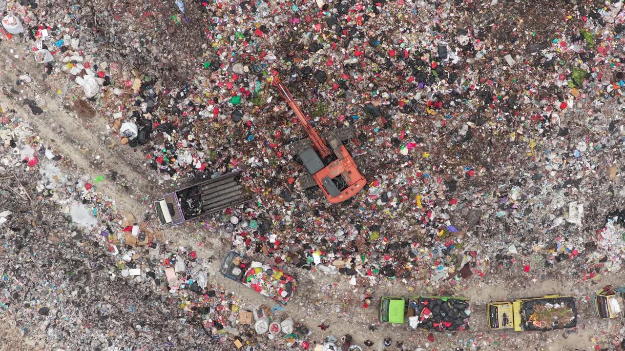 Vista aerea di un escavatore che carica i rifiuti in una grande discarica.