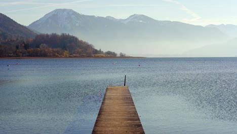 jetty pier on tegernsee in autumn with snow capped mountains of the alps in the background