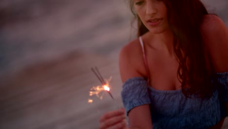 beautiful young woman on summer vacations holding sparklers after sunset