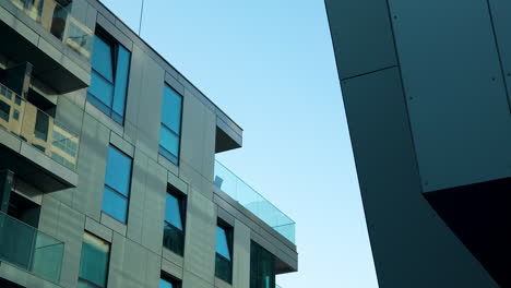 edificio moderno angular con balcones de vidrio contra un cielo despejado