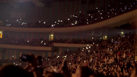 audience waving hands and mobile flashlights at the concert