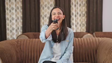 happy indian girl watching something funny on tv