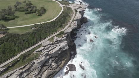 Menschen,-Die-Bei-Bondi-Nach-Bronte-Gehen,-Küstenweg-Mit-Brechenden-Wellen-Im-Sommer---Markiert-Den-Park-Und-Die-Halbinsel-Mackenzies-Point-In-Tamarama,-Nsw,-Australien