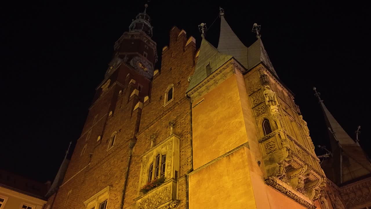 Illuminated night view of the historic Wroclaw Old Town Hall located in the vibrant market square, showcasing exquisite architectural details and atmospheric lighting.