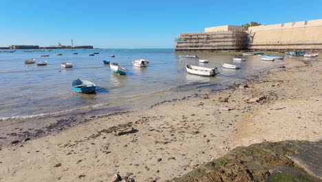 pequeños barcos amarrados cerca de las antiguas murallas marinas de cádiz
