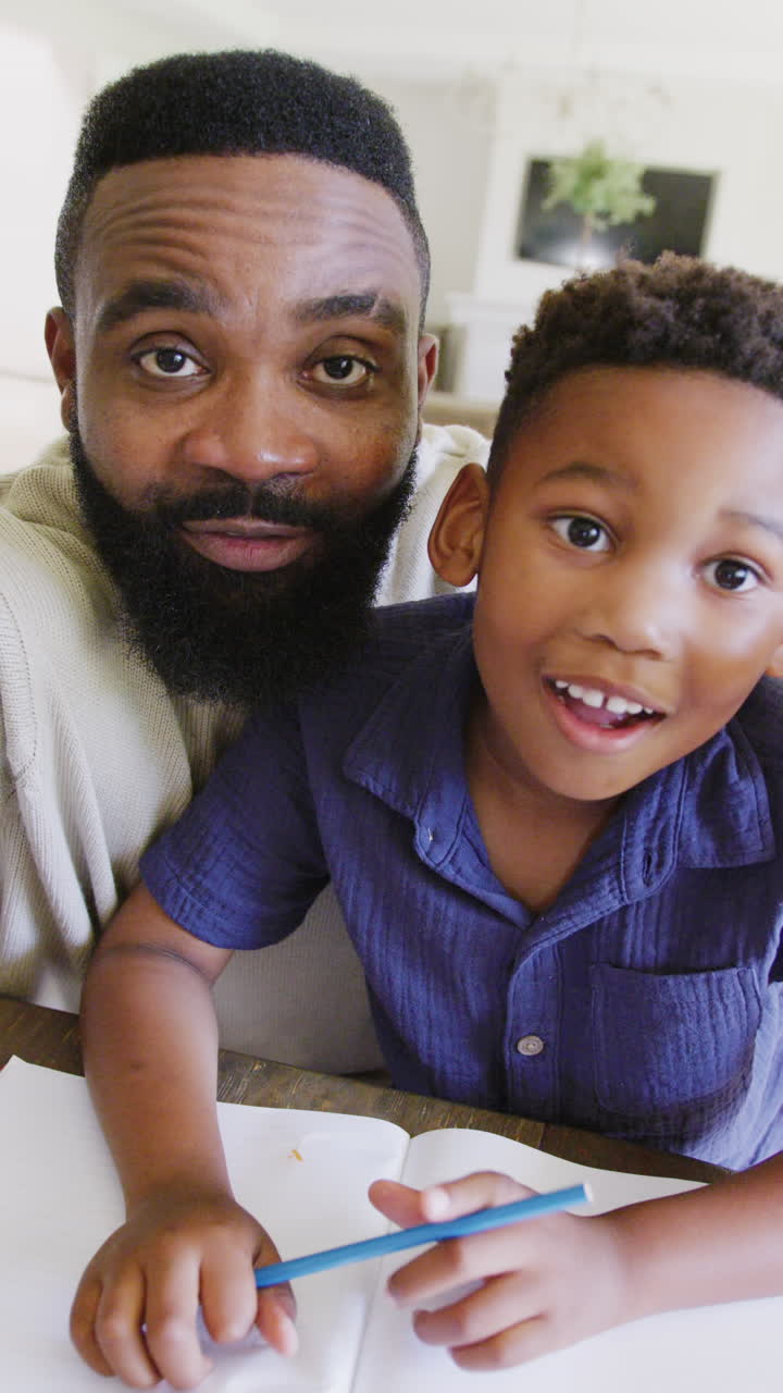Video verticale di padre e figlio afroamericani che fanno i compiti insieme, al rallentatore