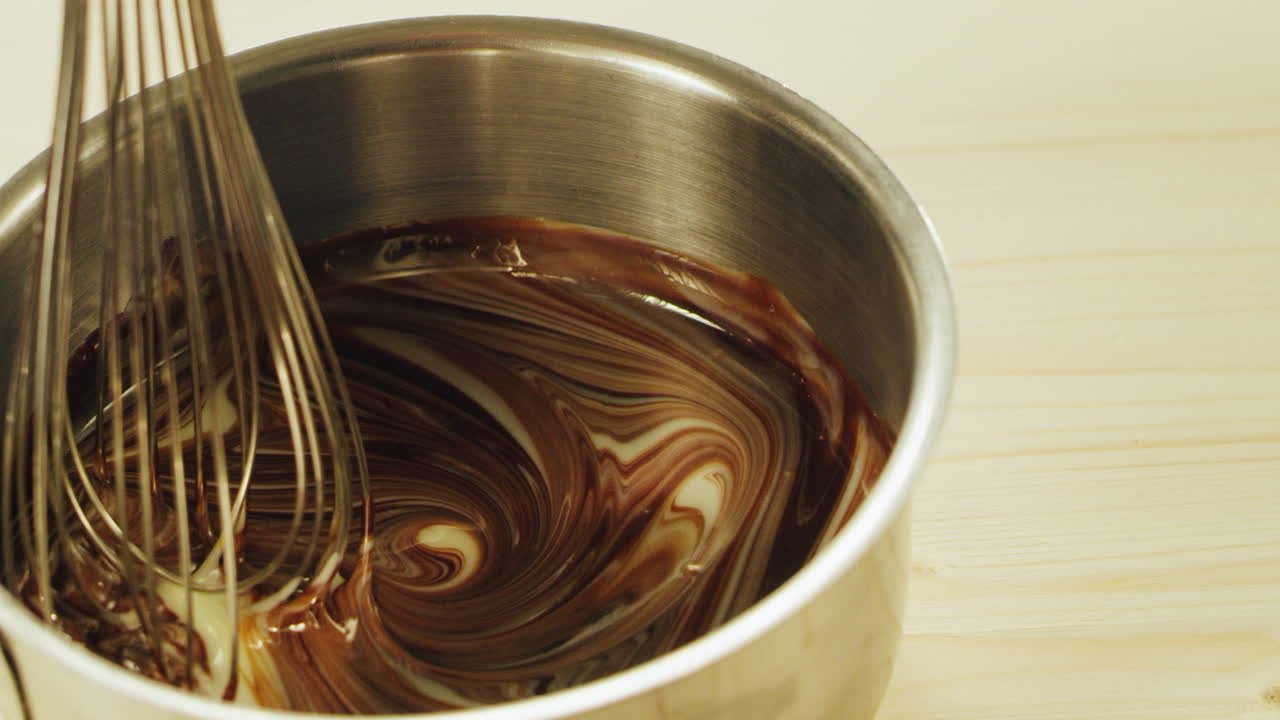 en primer plano, el chocolate derretido se mezcla con el batidor en cámara lenta.