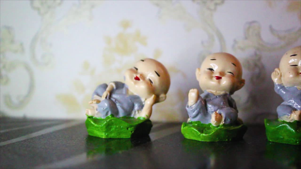 Closeup of four smiling monk figurines in peaceful poses. Symbol of Zen, joy and mindfulness. Ideal for decor, spirituality or meditation themes.