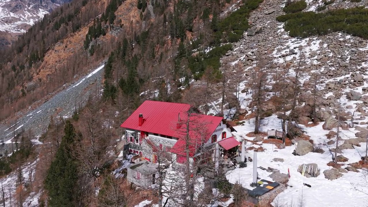 Malownicze ujęcie z lotu ptaka uroczej górskiej chaty położonej w zaśnieżonym krajobrazie Alpe Ventina zimą