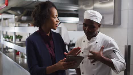 gerente femenina afroamericana usando una tableta y hablando con el chef