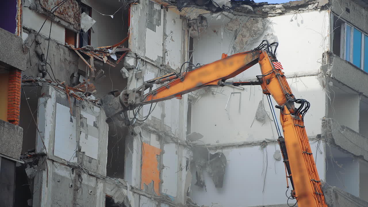 Une machine spéciale détruit la maison. Une pelleteuse de démolition démolit un ancien bâtiment.