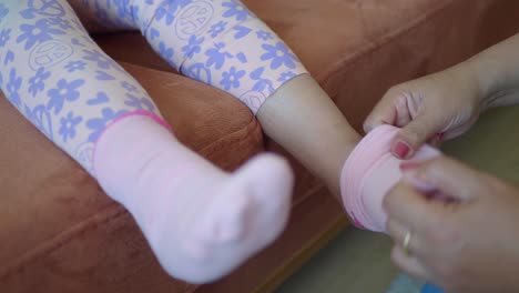 mother putting socks on her toddler daughter