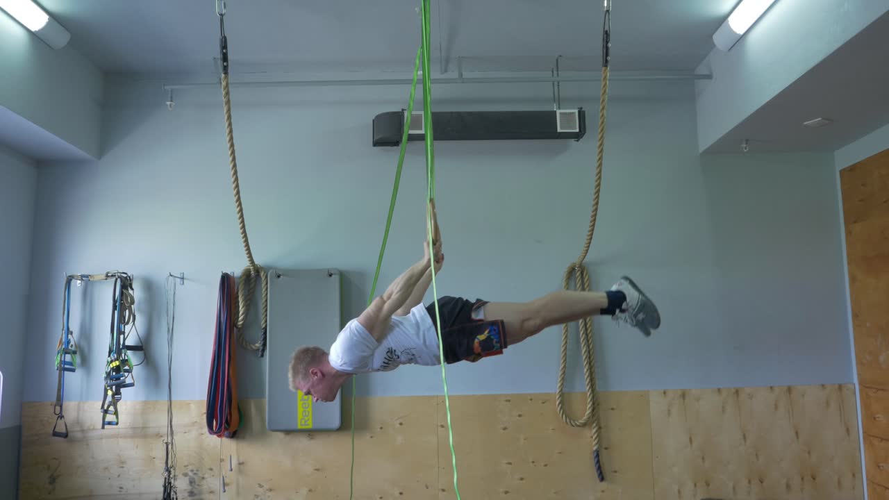 남자 가 체육관 에서 링 을 통해 허리 운동 을 하고 있다