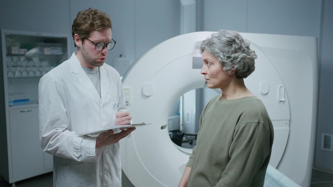 Medico uomo che parla con un paziente e scrive la cartella clinica prima di un esame di diagnostica per immagini.