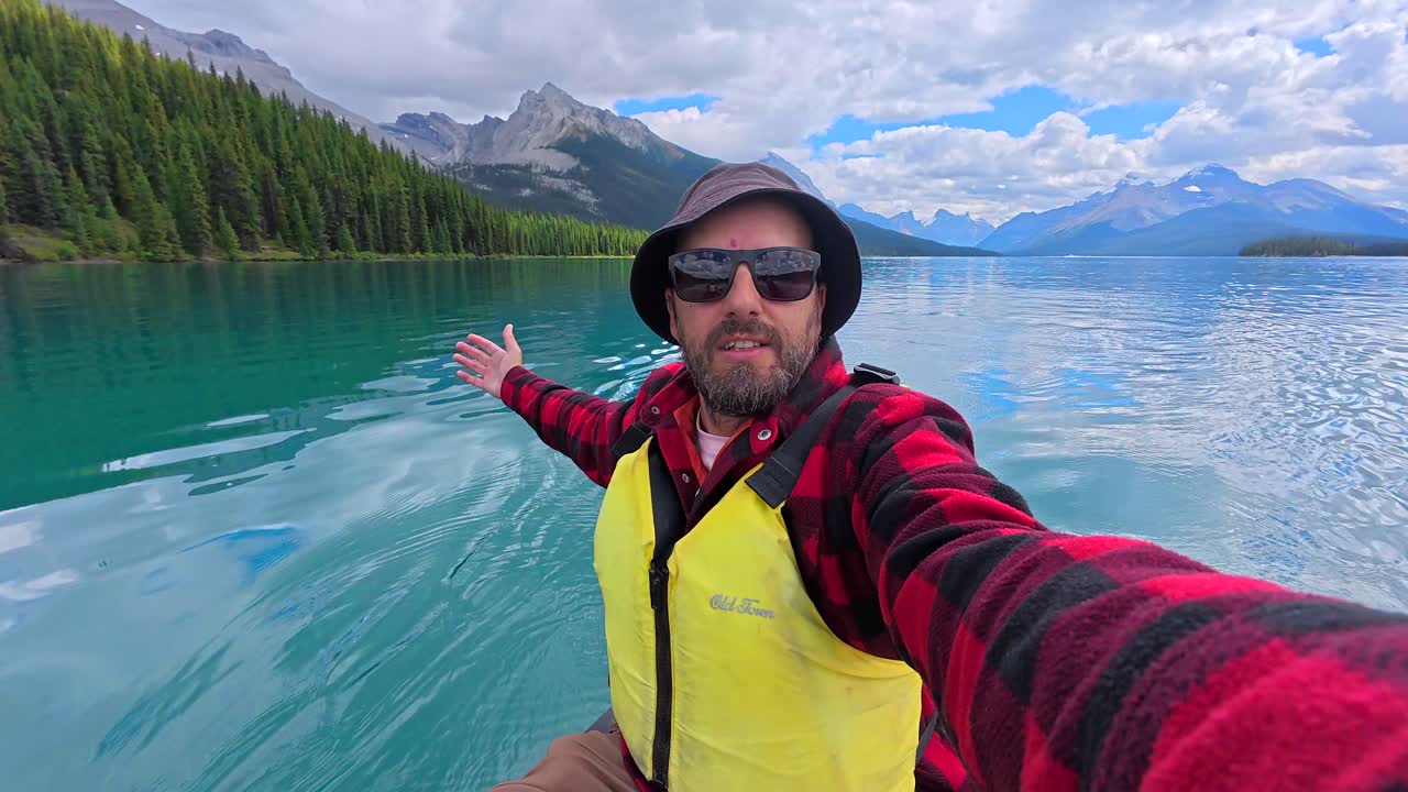 Homem andando de canoa em um lago cercado por montanhas e floresta