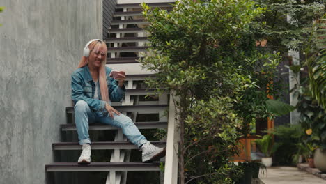 young woman enjoying a phone call and music on stairs