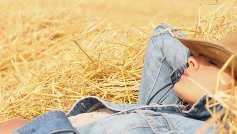 peaceful woman with cowboy hat lying in hay