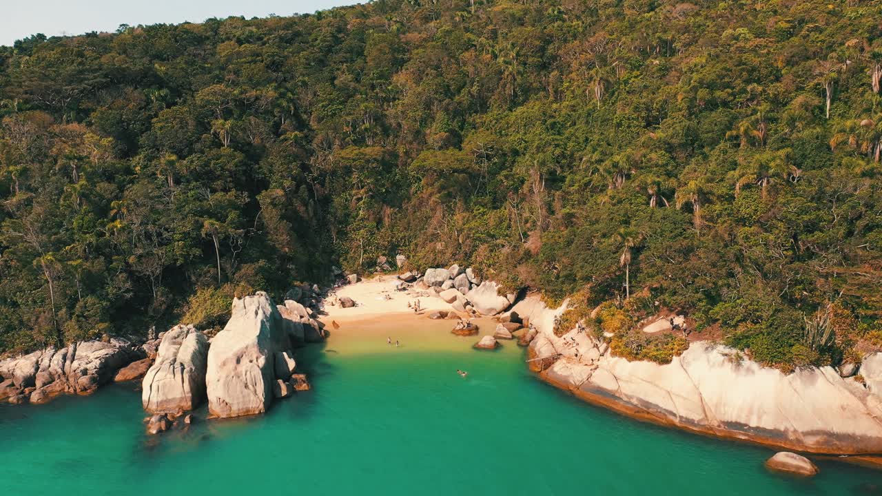 Vista aerea che si avvicina a una spiaggia paradisiaca segreta brasiliana con acqua color turchese situata a Bombinhas, Santa Catarina, Brasile