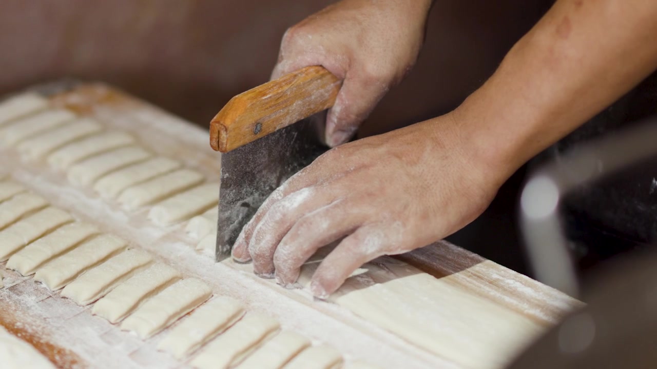 Baker Cutting Dough Strips for Traditional Pastry Preparation