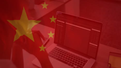 animation of flag of china over caucasian businesswoman using laptop