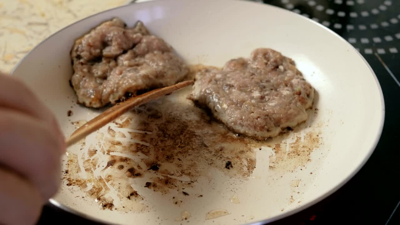 한 남자가 햄버거를 위해 팬 코틀에 고 있습니다. 손을 가까이 어보세요.