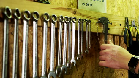 Human hand takes vernier caliper from wall. Set of mechanical tools in garage