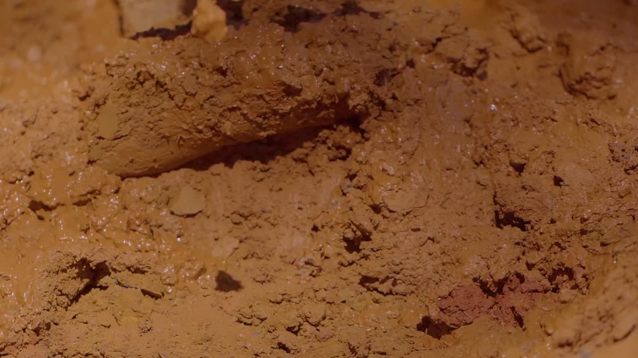 Construction worker from Kalunga community mixing earth with bare feet, creating adobe bricks using traditional bioconstruction technique in Chapada dos Veadeiros, Brazil, preserving cultural heritage