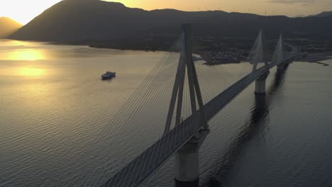 aerial - rio antirrio bridge in greece at sunset with boat passing by in the background - shot on dji inspire 2 x7 raw