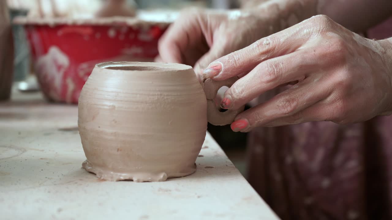 una joven hace una jarra de arcilla. las manos de las mujeres moldean la cerámica.