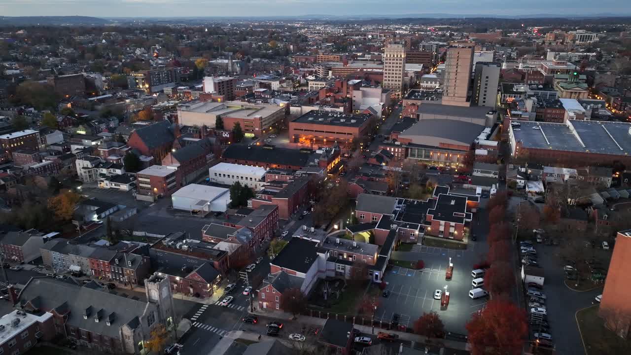 Ripresa aerea in avvicinamento di Main Street con auto in transito al crepuscolo. Case e abitazioni storiche vicino al centro di una città americana. Campo lungo. Tempo sereno nella stagione invernale.