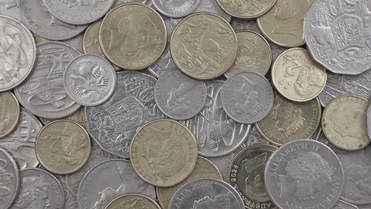 Una gran pila de monedas australianas usadas gira frente a la cámara en una toma de primer plano en 4K