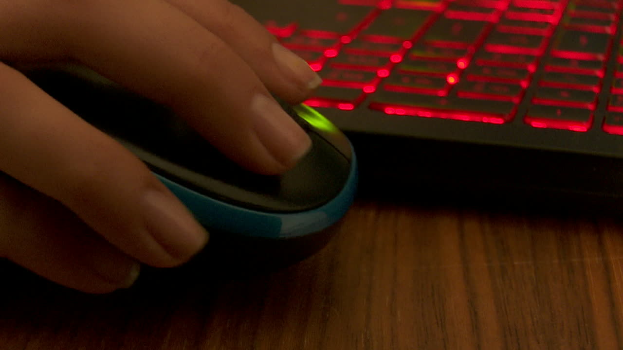 Person using a laptop with a red-lit keyboard and mouse