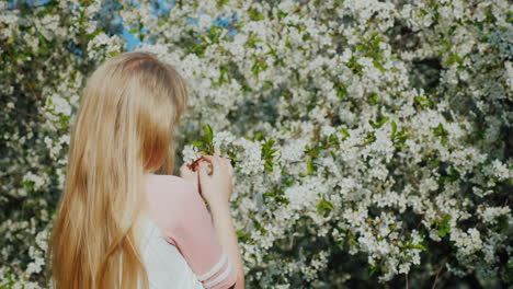 girl admires a flowering tree the arrival of spring and heat