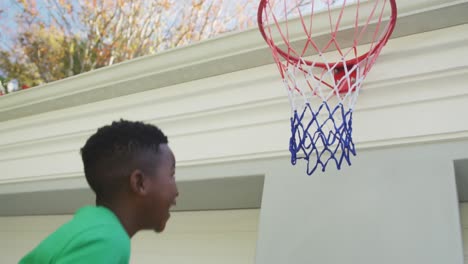 african american dad carrying his son to make a dunk in the basketball hoop