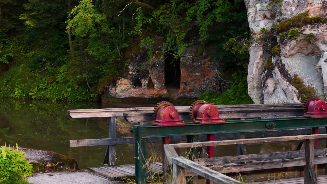 Slussar nära mycket gamla grottor vid Ligatneälvens stränder, Lettland. Flygande kamerarörelse åt vänster.