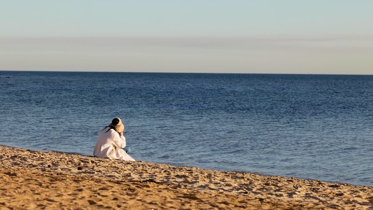 A girl sits alone on Brighton beach