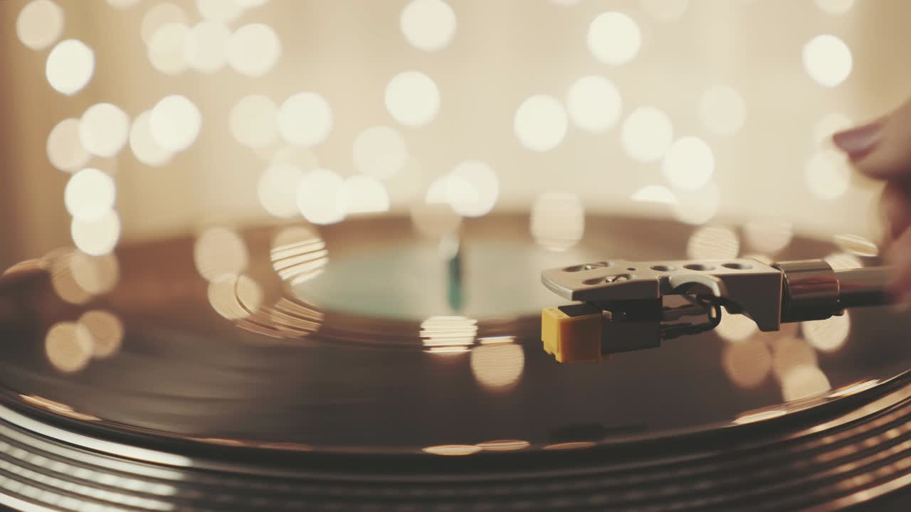 회전하는 블랙 비닐 레코드 플레이어의 조각, 회전하는 판과 바늘 회전 테이블을 가진 스타일러스, 흐릿한 밝은 불빛, 손 소녀는 비닐 레코드를 넣고 그라모폰을 포함합니다.