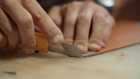 close-up of hands cutting leather