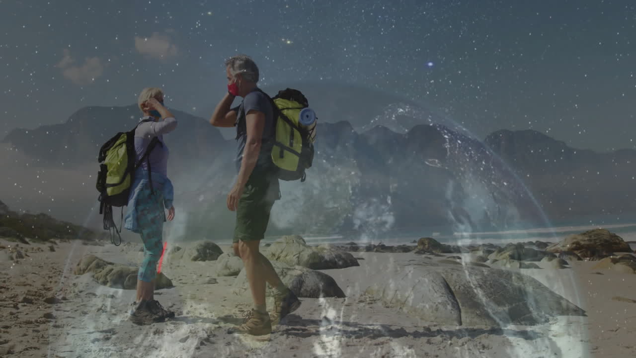 Woman hiker and man hiker exchanging fist bump on rocky beach, with digital technology overlay
