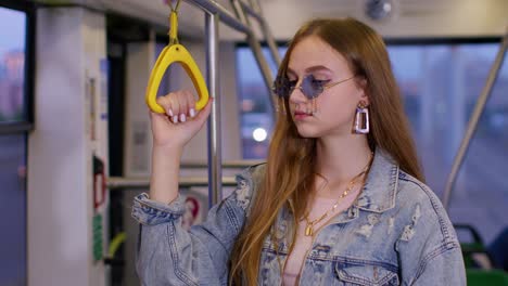 attractive young woman passenger riding at public modern bus or tram transport, looking out window