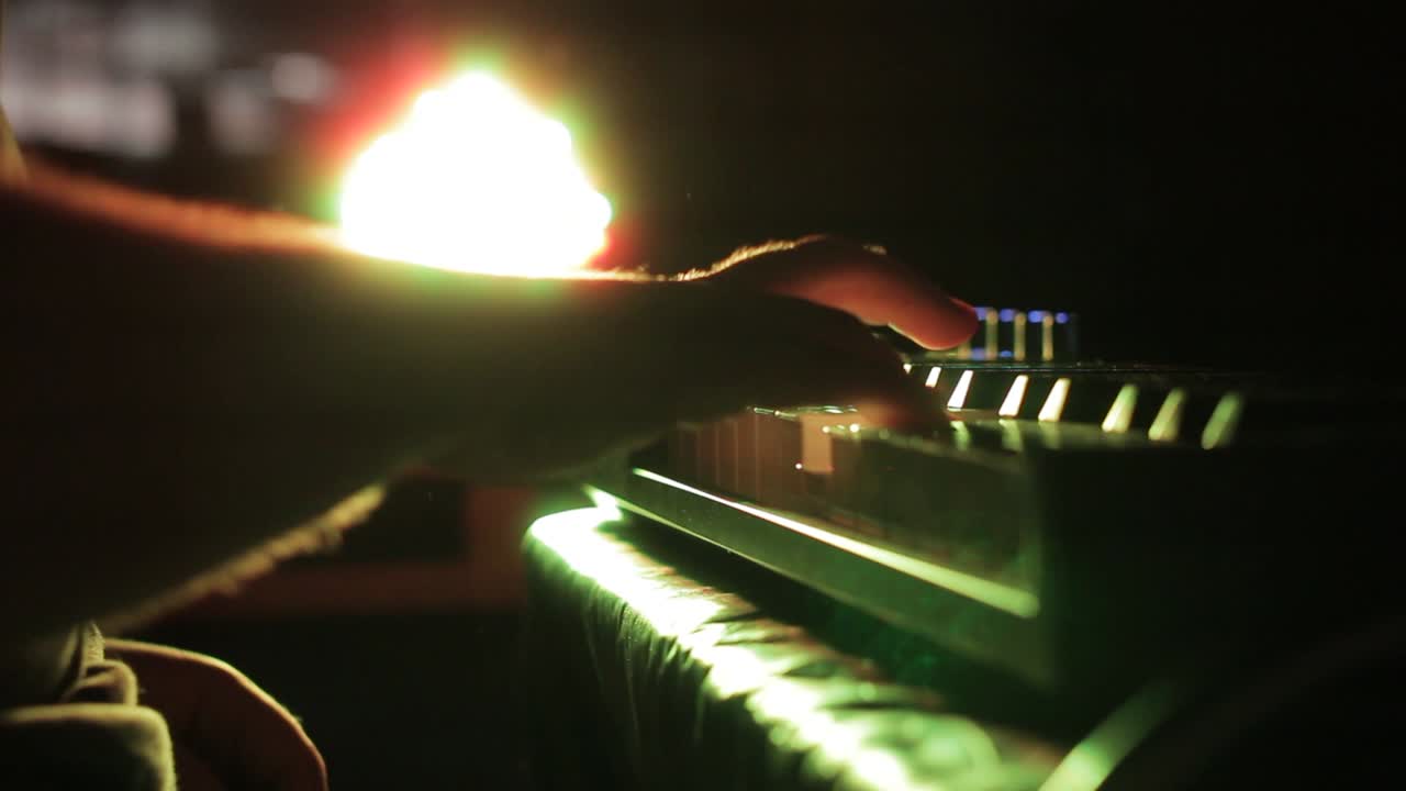 Musician's hand playing keyboard in front of colorful strobe light. Talented artist shows off keyboard skills