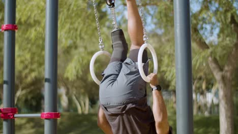 strong man with artificial leg doing gymnastic rings workout.