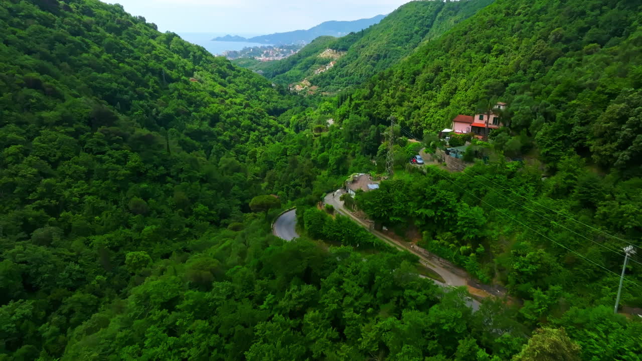 Sorvolo di droni su case e una strada di montagna, verso Rapallo, in una giornata estiva in Italia