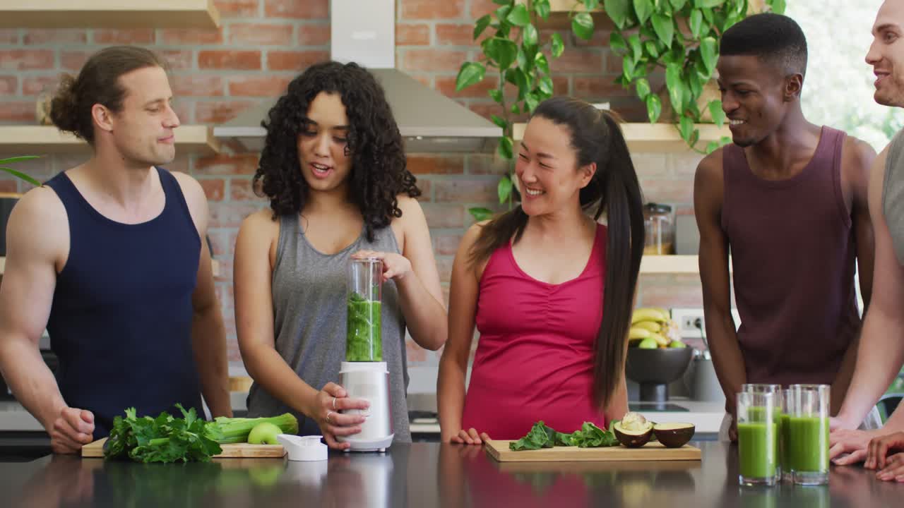 grupo de jóvenes diversos haciendo un batido verde y saludable juntos en casa