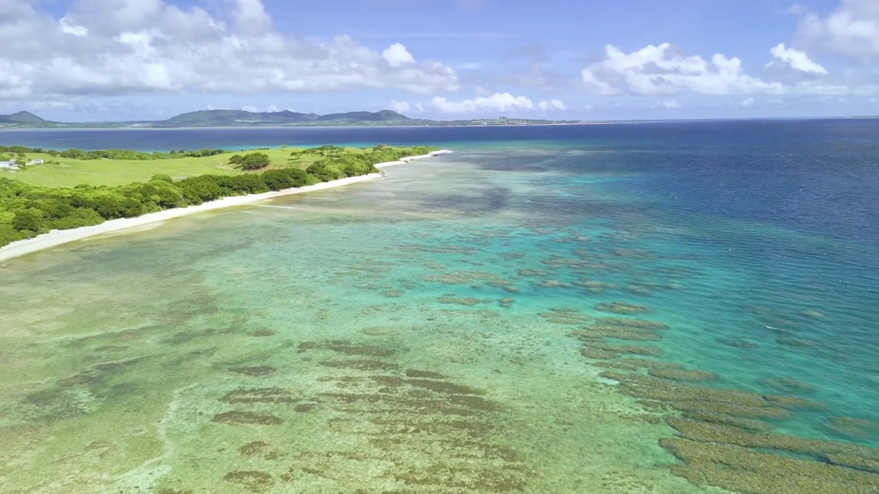 Ampia veduta aerea con drone della costa di Ishigaki, con vaste formazioni coralline e acque turchesi.