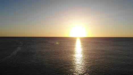 aerial view of golden yellow sunset over the ocean water towards horizon