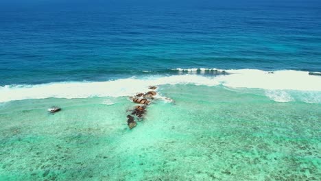 mahe seychelles anse forbans beach, drone shot moving towards middle rocks turquoise water