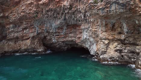 aerial approaches cave in adriatic sea cliff on coast of montenegro