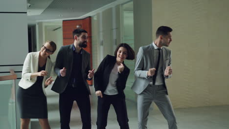 business team dancing in office corridor